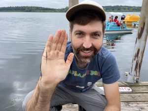 A volunteer crouched on a boardwalk holding up an AIS.