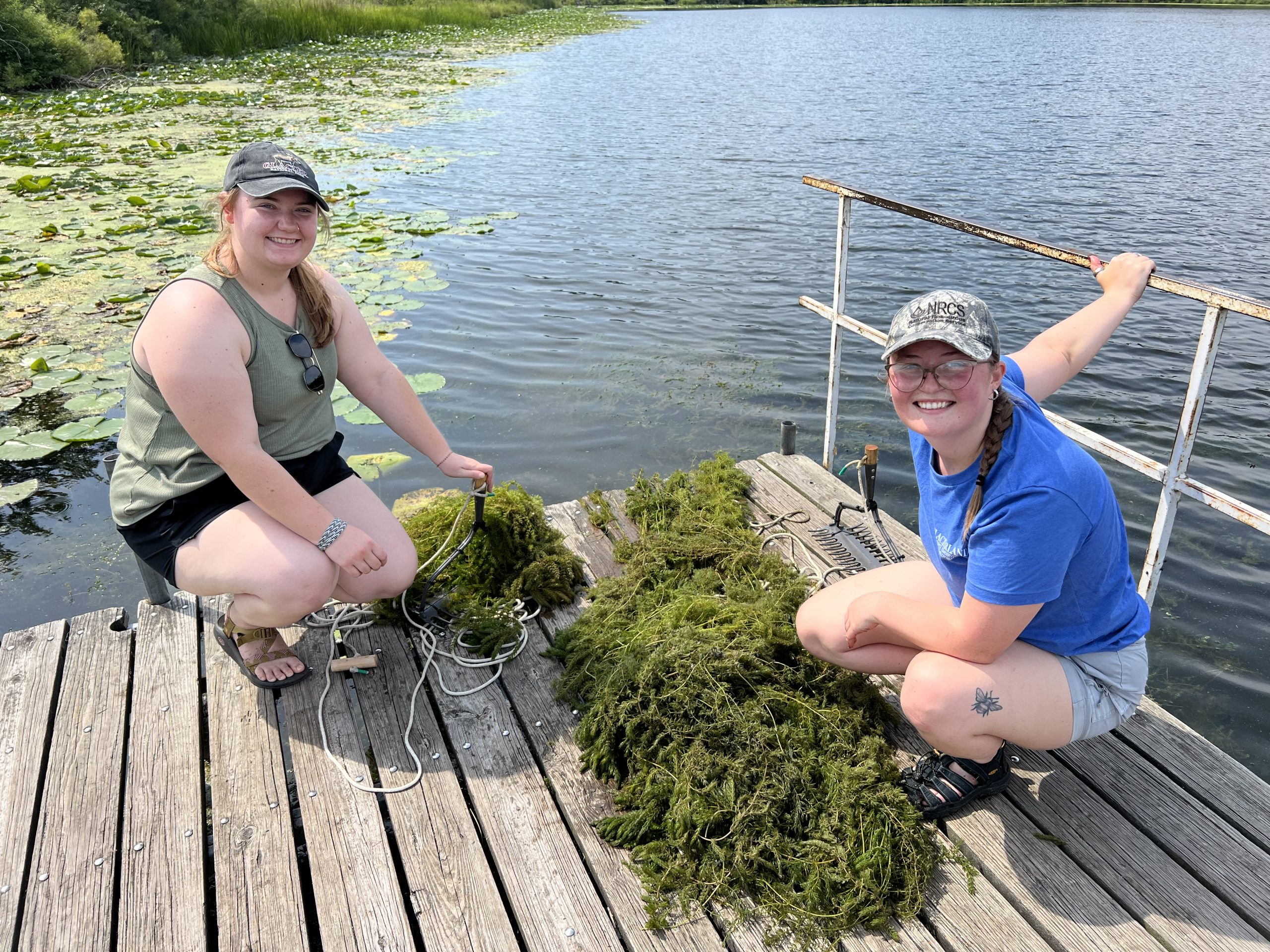 Two volunteers stand on a dock surrounded by AIS. 