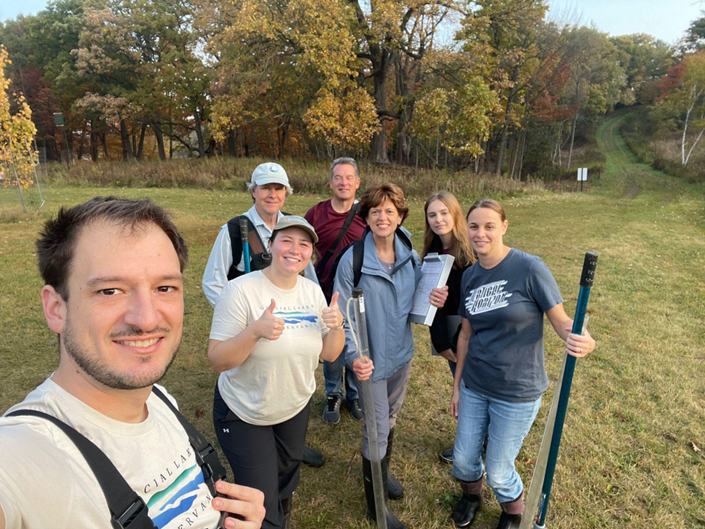A group of volunteers standing on a grass path in a forest.